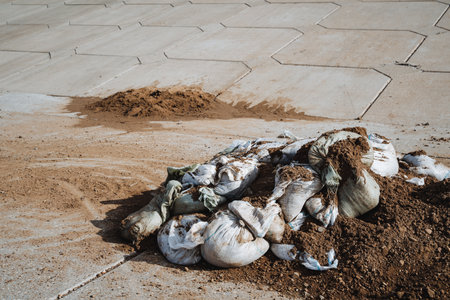 Discarded sandbags and scattered soil on urban pavements indicate significant waste management challenges and environmental impacts cities face in their pursuit of sustainabilityの写真素材