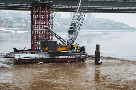A graceful crane elegantly stands on a small raft swaying in calm waters beneath a strong bridge, highlighting the harmonious connection between natures beauty and human engineeringの写真素材