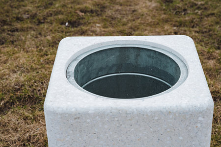 A square trash can on a maintained green lawn enhances aesthetics and functionality. Its durable concrete design ensures stability in all weather, making it ideal for parks and gardensの写真素材
