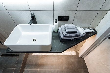 This welldesigned bathroom showcases a stylish modern sink along with neatly organized towels, effectively promoting hygiene, comfort, and relaxation for all users who utilize the spaceの写真素材
