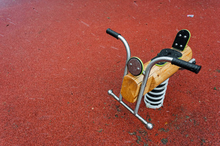 An intricately crafted wooden rocking horse is beautifully positioned on a vibrant red surface, perfect for imaginative play and creating a sense of balance, ideal as outdoor play equipmentの写真素材