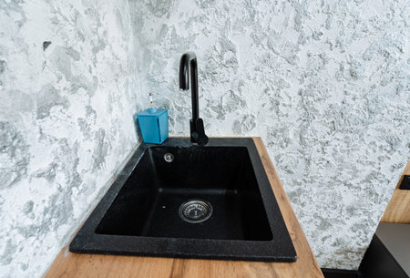 A beautifully designed kitchen features a striking black sink on a sturdy wooden counter, combining functionality and style while enhancing the overall aesthetic appeal of the spaceの写真素材