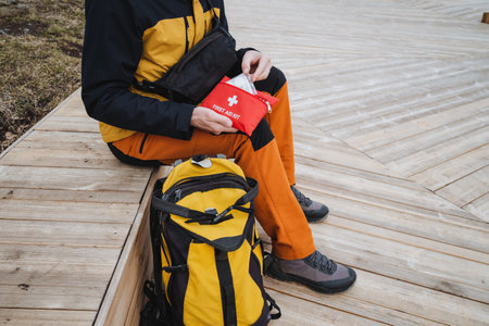 A dedicated hiker prepares an emergency kit on wooden planks, showcasing vibrant gear and demonstrating impressive readiness for the thrilling outdoor adventure in natureの写真素材