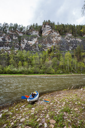Imagine a serene scene with a kayak on a pebblestrewn shore, framed by cliffs and greenery along a peaceful river. Its a perfect spot for outdoor enthusiasts seeking adventure or relaxationの写真素材