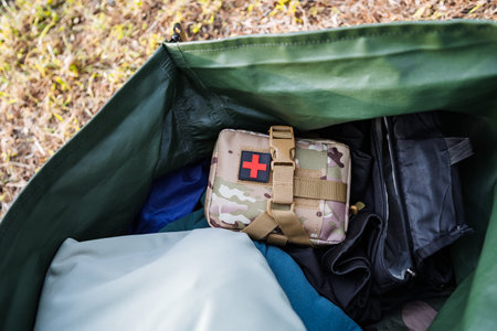 A wellorganized outdoor gear bag with a prominently marked camouflage first aid kit is filled with essential items, making it perfect for adventures and effective emergency preparednessの写真素材