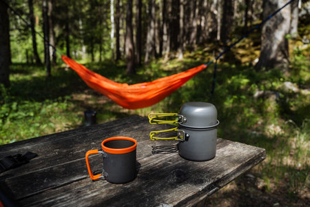 Nestled in a peaceful wooded area, a cozy hammock gently sways above a rustic picnic table, crafting an ideal location for relaxation and for savoring the breathtaking beauty of nature all aroundの写真素材