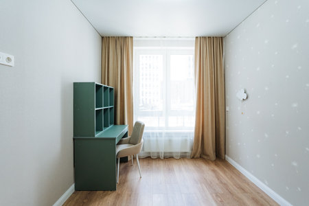 In this empty room, a simple desk and chair are positioned by a window, letting natural light fill the space and create a bright, inviting atmosphere for productivity and relaxationの写真素材
