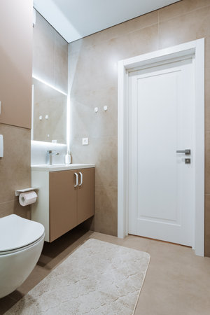 The bathroom is designed with essential fixtures a convenient toilet, an effective sink for handwashing, and a mirror for grooming, ensuring a pleasant and comfortable hygiene experienceの写真素材