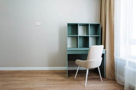 A singular chair positioned at a desk located by the window permits an abundance of natural light to stream in, thereby significantly enhancing the overall atmosphere and aesthetic design of the roomの写真素材