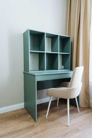 In a wellfurnished room, there is a sturdy desk, accompanied by a comfortable chair and an organized bookshelf filled with various items, creating an inviting and functional working spaceの写真素材
