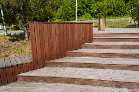 A beautifully crafted wooden staircase, made with attention to detail, leads to a sturdy wall in a serene park, showcasing its charm and inviting visitors to explore the peaceful surroundingsの写真素材