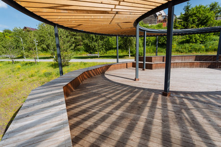 A beautifully crafted wooden deck featuring a sturdy wooden roof, all located within a vibrant park setting. This inviting space is perfect for relaxation and social gatherings amid natureの写真素材