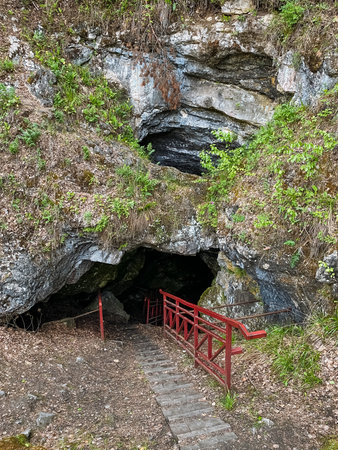 A fascinating cave features a set of stairs leading right down into it, complemented by a bright red railing that provides safety and support for those who dare to exploreの写真素材