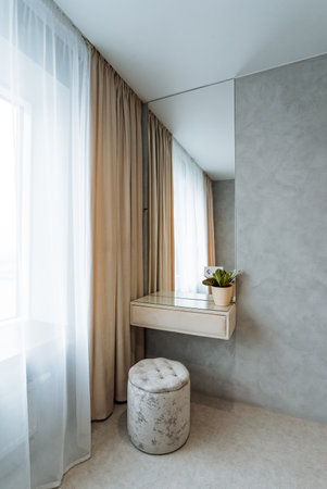 In the room, there exists a stylish dressing table that features a mirror and a comfortable stool, enhancing the overall aesthetic of the space and complementing the interior design perfectlyの写真素材