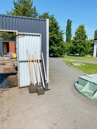 A collection of several shovels can be found resting outside the entrance of a building, seemingly waiting to be used for various tasks, such as digging in the backyard or drivewayの写真素材