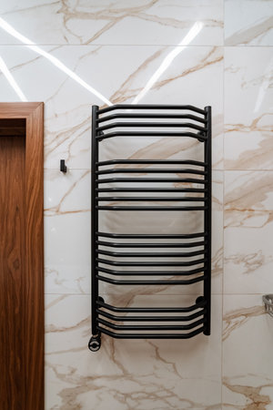A sleek, modern black towel rack is elegantly hanging on a stunning marble wall in a stylish bathroom, adding a touch of contemporary design to the overall decor and functionality of the spaceの写真素材