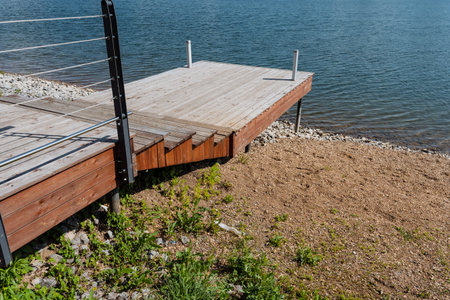A sturdy wooden dock by the tranquil lake invites visitors to enjoy breathtaking views, warm sunlight, and the soothing sounds of nature, offering a perfect escape from daily lifeの写真素材