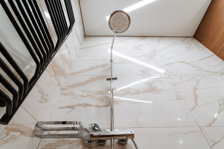 A stylish shower head is positioned above a beautifully tiled floor in a contemporary bathroom, enhancing functionality and contributing to its chic ambiance and overall aesthetic appealの写真素材