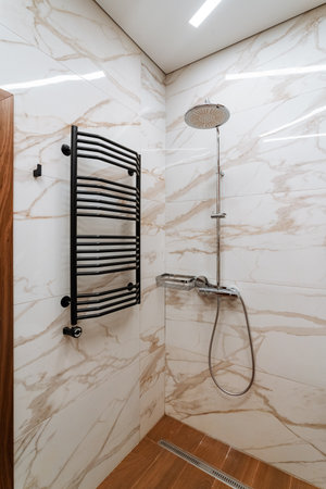This is a bathroom that features a towel rack for hanging towels neatly and a shower head for bathing. It combines various essential elements like flooring and essential plumbing fixturesの写真素材
