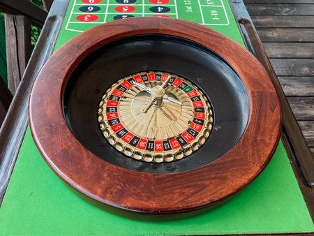 A beautifully crafted wooden roulette wheel is prominently displayed, resting on a vibrant green mat that adds to the allure of the scene, creating an inviting atmosphere for gaming enthusiastsの写真素材