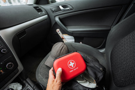 A person is currently holding a bright and vividly colored red first aid kit in their vehicle, ensuring they are well prepared for any potential emergencies that may arise while traveling on the roadの写真素材