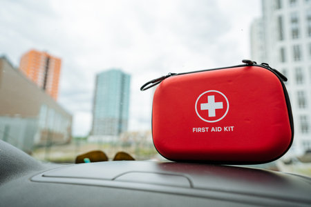 A bright red first aid kit is prominently sitting on the dashboard of a car, ready for any potential emergencies that may require immediate health care and assistance with first aid measuresの写真素材