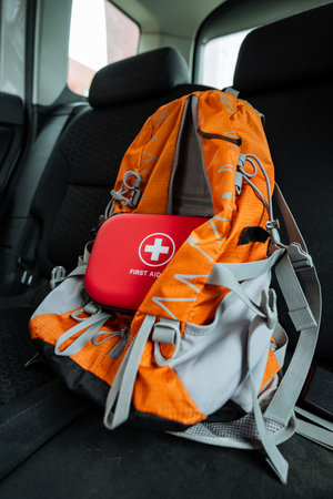 There is a backpack equipped with a first aid kit placed conveniently in the back seat of a passenger car, ensuring readiness for any emergencies during travel or outdoor adventuresの写真素材