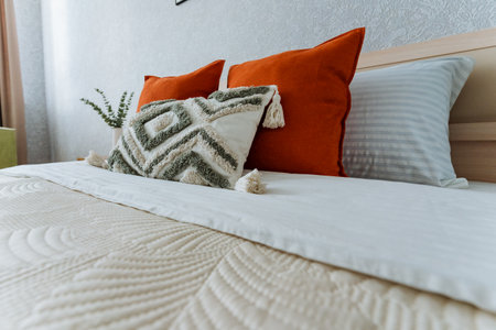 A beautifully crafted bed adorned with a soft, pristine white comforter and a generous supply of fluffy pillows, together creating a cozy, warm, and inviting atmosphere in the elegant bedroom spaceの写真素材