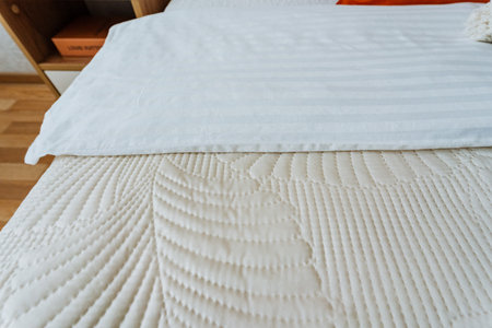 This beautifully designed room features crisp white sheets and a cozy quilt, creating a serene atmosphere that enhances the bedrooms ambiance, making it a perfect retreat for relaxationの写真素材