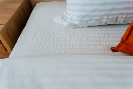 A beautifully made bed featuring crisp white sheets and fluffy pillows arranged perfectly on it, creating a serene and inviting atmosphere that enhances the overall ambiance of the bedroomの写真素材