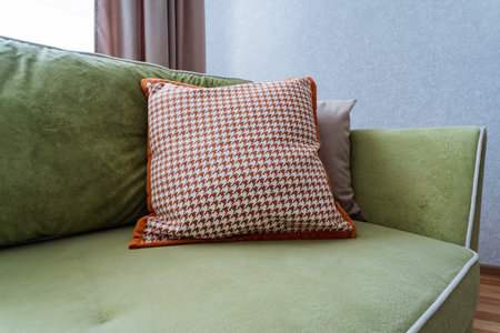 A vibrant green couch adorned with a bright orange pillow resting on it, creating a lively contrast that enhances the overall aesthetics of the room, making it a focal point in the interior designの写真素材