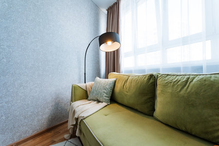 This living room features a cozy green couch accompanied by a stylish lamp, creating a warm and...
