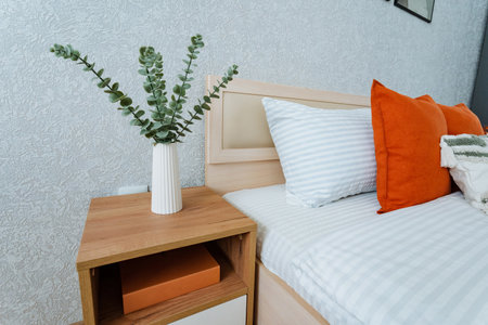 The cozy bedroom is furnished with a comfortable bed, accompanied by a stylish nightstand that features a vibrant plant on top, creating a serene atmosphere for relaxation and restの写真素材