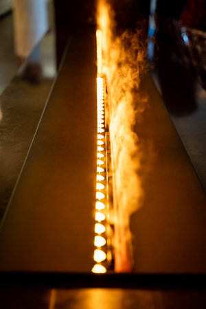 A stunning closeup of a modern cooking grill shows vibrant flames and rising steam, creating an...