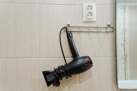 A sleek hair dryer is wellorganized and neatly placed on a beautifully designed wallmounted rack, creating an elegant and sophisticated setup for personal care within a stylish and modern bathroomの写真素材