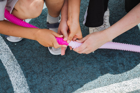 A lively group of energetic children are happily playing together with an engaging and fun pink toy...
