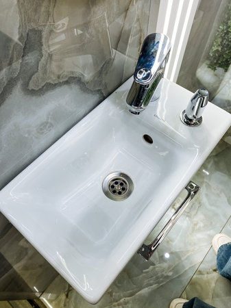 This elegantly designed bathroom sink features a contemporary faucet and stylish mirror, creating a...