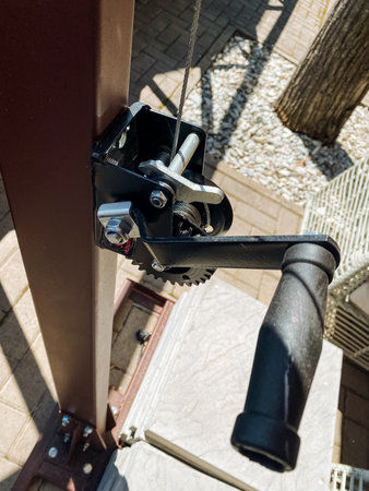This image depicts a detailed closeup view of a winch that is mounted on a sturdy pole, showing its mechanical components and the way it is integrated into its support structureの写真素材