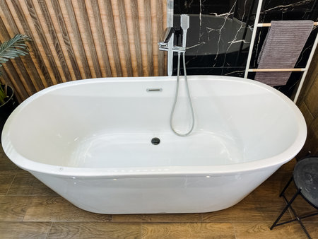 In a beautifully designed bathroom, a pristine white bathtub is elegantly positioned on a polished wooden floor that adds warmth and character to the space, creating a serene atmosphereの写真素材