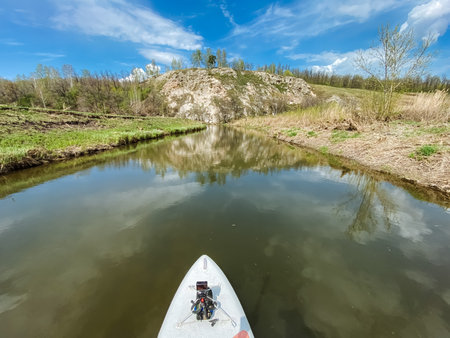 A person is skillfully paddling a brightly colored kayak on a flowing river, thoroughly enjoying the stunning beauty of nature and the picturesque scenery that surrounds them on all sidesの写真素材
