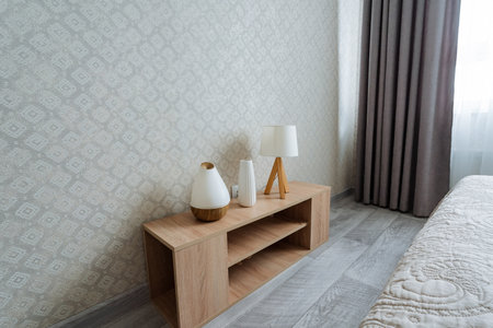 This cozy bedroom features a comfortable bed for relaxation and a charming wooden table with stylish lamps, creating a warm and inviting ambiance perfect for unwinding after a long dayの写真素材