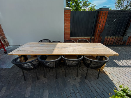 This beautifully designed outdoor space features a charming wooden dining table with elegant black chairs, offering a warm setting ideal for gatherings and delightful alfresco diningの写真素材