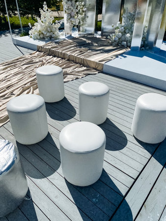 A group of white ottomans is positioned on a wooden deck, adding a touch of elegance and comfort to the outdoor space where people can gather and relaxの写真素材