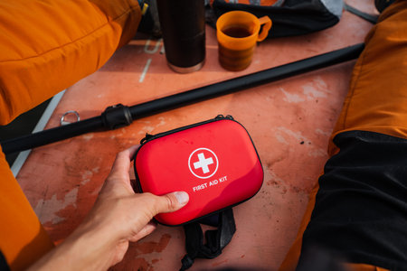 A person is confidently gripping onto a bright red first aid kit, emphasizing its vital role as an...