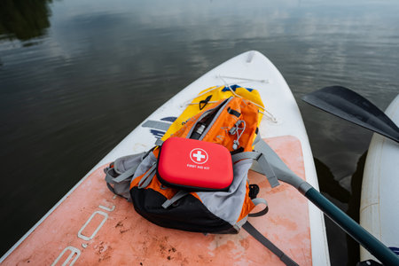 A bright red first aid kit is resting on the surface of a paddle board, ready for use in case of any...