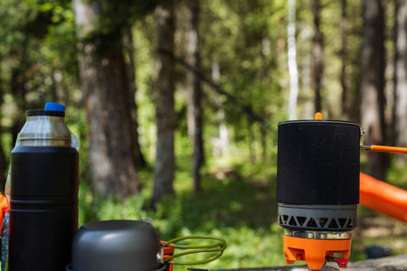 A camping stove is currently positioned on a sturdy table, nestled within the serene atmosphere of...