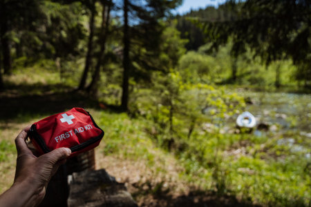 A person confidently holds a first aid kit in the woods, prepared for emergencies during their outdoor adventure, ensuring safety while exploring nature and maximizing their experienceの写真素材