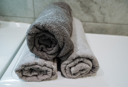 In the bathroom, three fluffy towels on the counter add elegance and charm. Their soft textures and colors enhance the decor, creating an inviting atmosphere for anyone who entersの写真素材