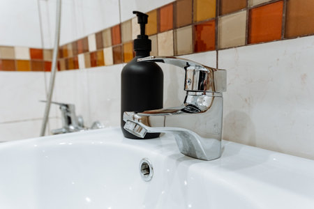In the bathroom, you will find a sink that is proficiently equipped with both a convenient soap dispenser and a faucet, ensuring easy and quick access to both water and soap at all timesの写真素材