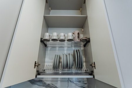 In reality, the kitchen cabinet is brimming with an assortment of plates, cups, and various utensils, showcasing a blend of functionality and design elements to enhance the kitchen spaceの写真素材
